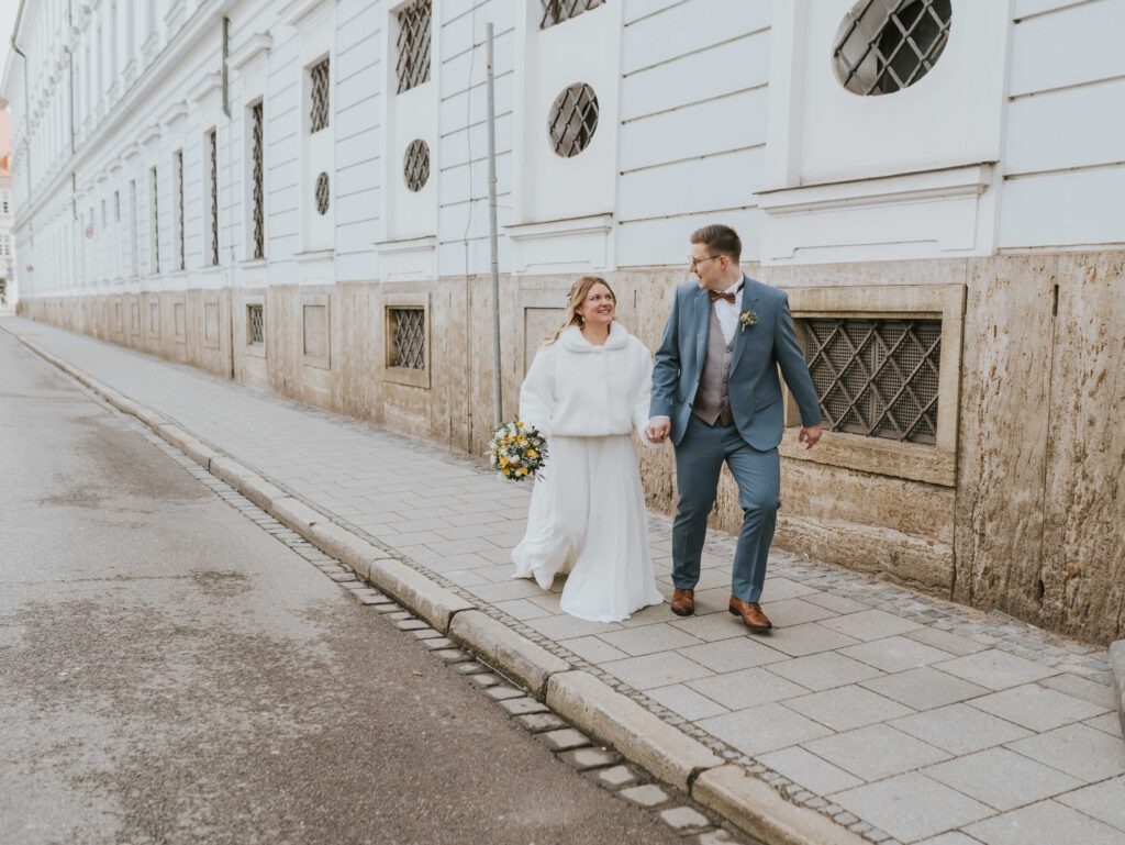 Dynamische Hochzeitsreportage Augsburg – Brautpaar rennt lachend im Freien